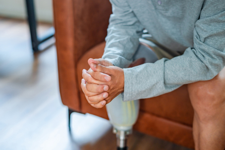 Disabled man wearing a prosthetic leg sitting on sofa at home