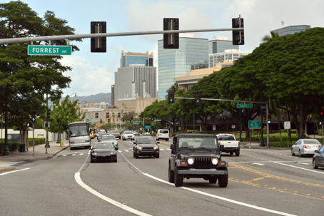 Mid-day traffic on Ala Moana Blvd with the modern architecture of Honolulu in the background.